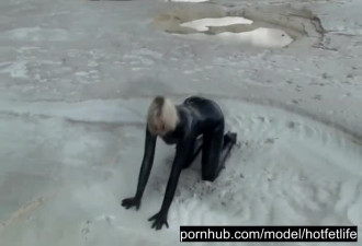 Super Hot Blond Girl in Black Latex Catsuit + High Heels and Sunglasses Bathes in the Mud - Mud Bath