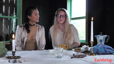 Older blonde MILF wearing glasses and younger brunette Asian girl on table lesbian